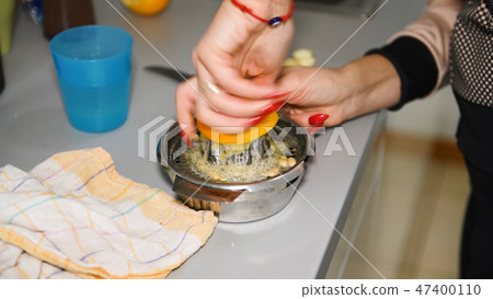 Woman squeezing lemon on countertop Woman squeezing lemon on countertop 47400110