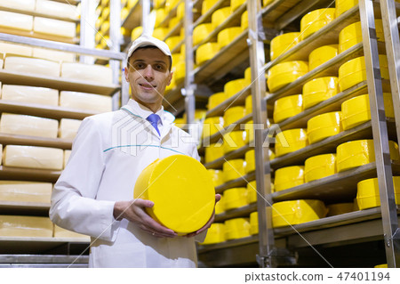man holding a head of cheese at a dairy plant 47401194
