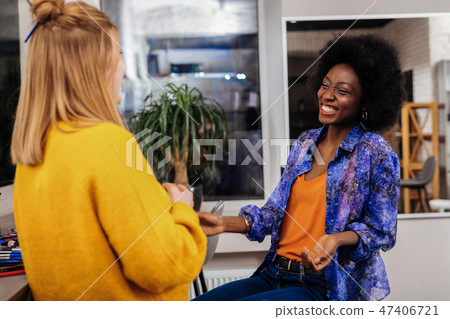 Beautiful dark-skinned stylist in an orange top laughing loudly 47406721