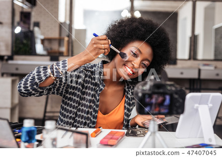 Pretty dark-skinned woman with bright makeup feeling amused 47407045