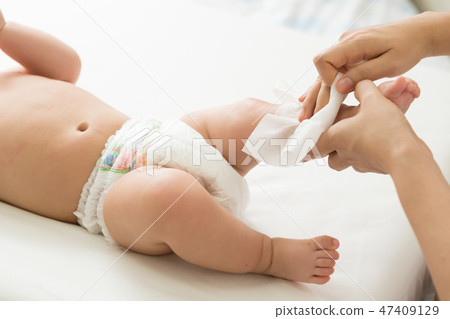 Mother cleaning up body and leg baby by wet tissue 47409129