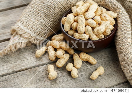 Peanuts in the shell, in a wooden cup on the table 47409674