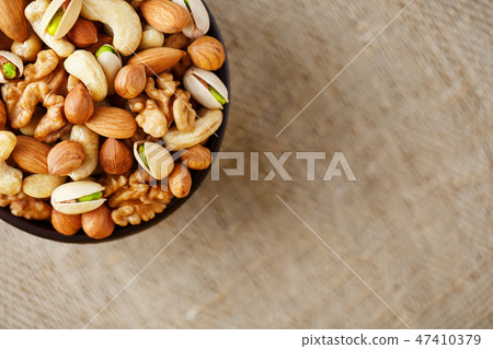 Mix of different nuts in a wooden cup against  47410379
