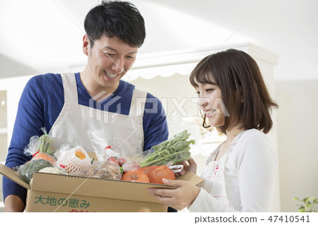 A husband who shows vegetables delivered in the kitchen to his wife 47410541