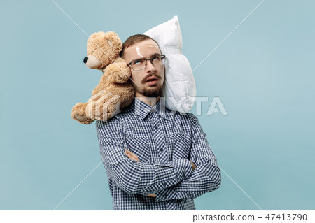 Tired man sleeping at home having too much work. Bored businessman with pillow and toy bear 47413790