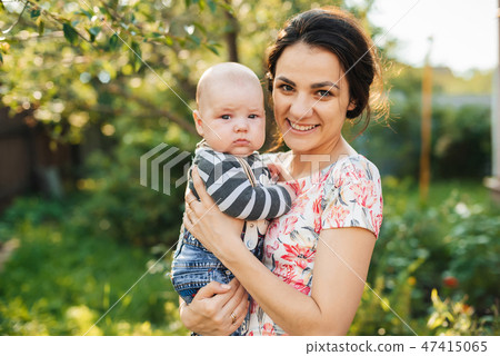 Happy young Caucasian mom with a boy newborn son in hands smiling Happy young Caucasian mom with a boy newborn son in hands smiling 47415065
