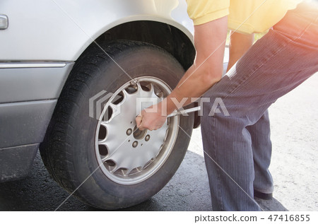 a man changes a wheel on a car outdoors a man changes a wheel on a car outdoors 47416855