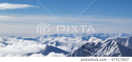 Panoramic view on snowy mountains in clouds 47417667