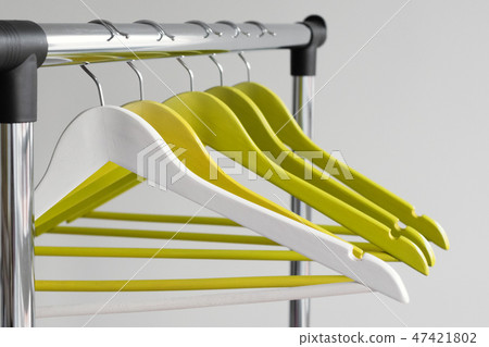 Empty clothes hangers on metal rail against grey background. Rectangular metal clothing rail with 47421802