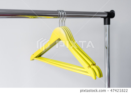 Empty clothes hangers on metal rail against grey background. Rectangular metal clothing rail with Empty clothes hangers on metal rail against grey background. Rectangular metal clothing rail with 47421822