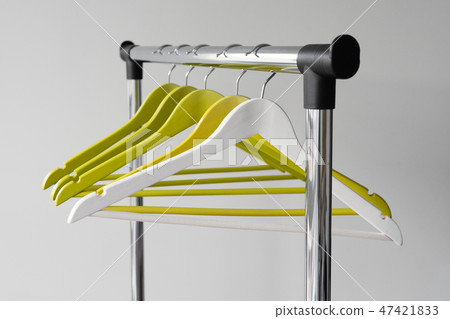 Empty clothes hangers on metal rail against grey background. Rectangular metal clothing rail with Empty clothes hangers on metal rail against grey background. Rectangular metal clothing rail with 47421833