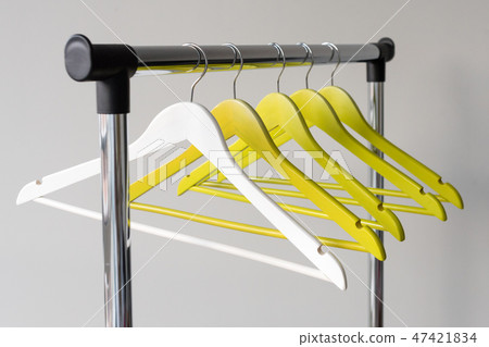 Empty clothes hangers on metal rail against grey background. Rectangular metal clothing rail with Empty clothes hangers on metal rail against grey background. Rectangular metal clothing rail with 47421834