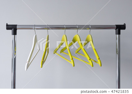 Empty clothes hangers on metal rail against grey background. Rectangular metal clothing rail with Empty clothes hangers on metal rail against grey background. Rectangular metal clothing rail with 47421835