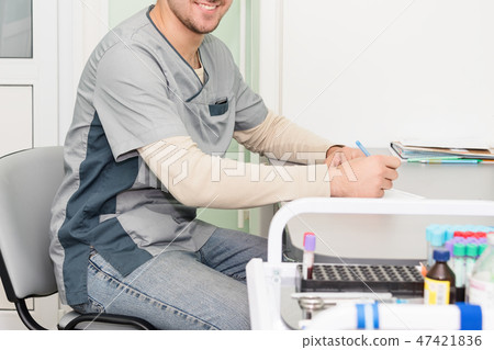 Doctor working, writing on paperwork. Modern hospital background. Doctor working, writing on paperwork. Modern hospital background. 47421836