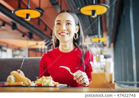 Businesswoman holding knife and fork while having lunch 47422748