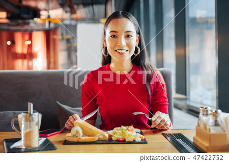 Dark-eyed woman eating delicious sandwich and salad in restaurant Dark-eyed woman eating delicious sandwich and salad in restaurant 47422752