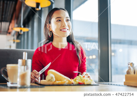 Close up of beaming appealing woman eating breakfast in cafe Close up of beaming appealing woman eating breakfast in cafe 47422754