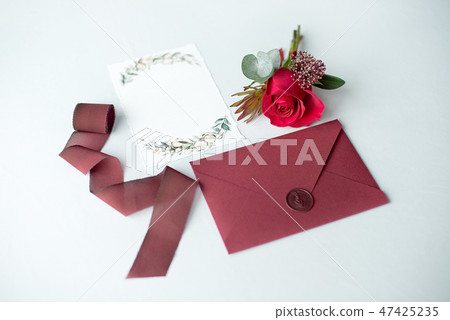 Wedding invitation as a decorated letter on a white tablecloth with a flower arrangement. Wedding invitation as a decorated letter on a white tablecloth with a flower arrangement. 47425235