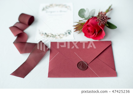 Wedding invitation as a decorated letter on a white tablecloth with a flower arrangement. Wedding invitation as a decorated letter on a white tablecloth with a flower arrangement. 47425236