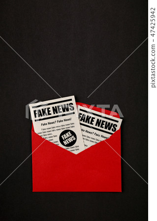 Envelope with FAKE NEWS newspapers over black 47425942
