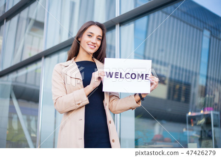 Businesswoman with long Hair Holding a sign Board with a Welcome has Airport Background 47426279