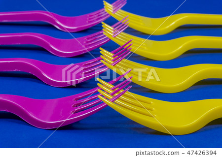 Colorful purple and yellow plastic forks on blue 47426394
