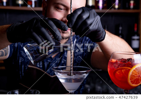 barman preparing and pouring cocktail in martini class. 47427639