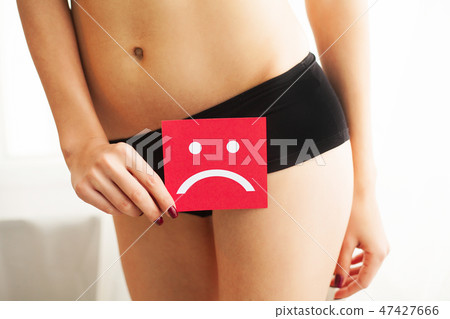 Vaginal or urinary infection and problems concept. Young woman holds paper with sad smile above 47427666