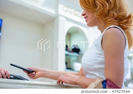 Wireless payment using smartphone and NFC technology. Close up. Female customer paying with smart 47427694