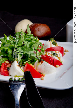 Caprese Italian or Mediterranean salad. Tomato mozzarella basil leaves and olive oil on black table. Caprese Italian or Mediterranean salad. Tomato mozzarella basil leaves and olive oil on black table. 47427830
