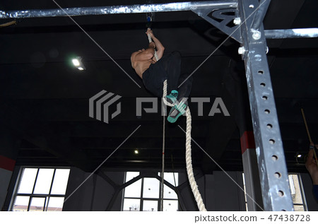 Crossfit athlete climbing the rope in gym 47438728