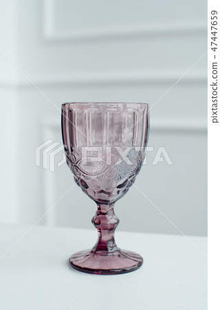 Embossed colored drink glasses for wine on a white wooden table. 47447659