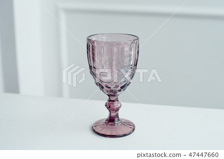 Embossed colored drink glasses for wine on a white wooden table. 47447660
