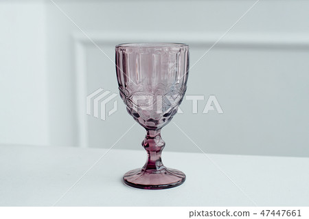 Embossed colored drink glasses for wine on a white wooden table. Embossed colored drink glasses for wine on a white wooden table. 47447661