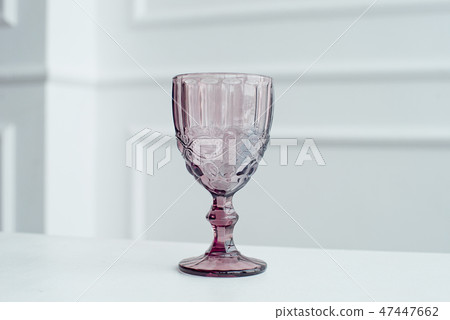 Embossed colored drink glasses for wine on a white wooden table. Embossed colored drink glasses for wine on a white wooden table. 47447662
