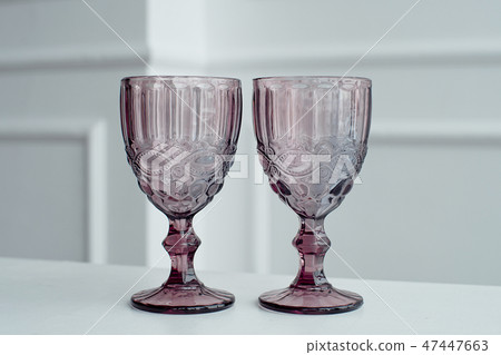 Embossed colored drink glasses for wine on a white wooden table. Embossed colored drink glasses for wine on a white wooden table. 47447663