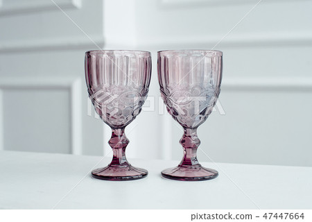 Embossed colored drink glasses for wine on a white wooden table. Embossed colored drink glasses for wine on a white wooden table. 47447664