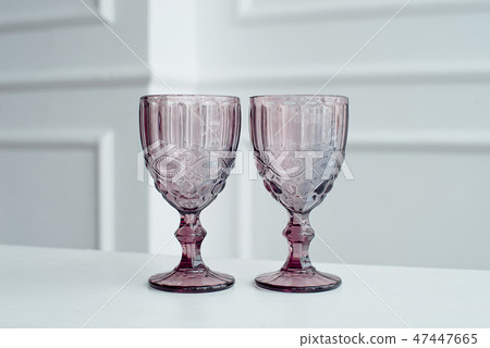 Embossed colored drink glasses for wine on a white wooden table. Embossed colored drink glasses for wine on a white wooden table. 47447665