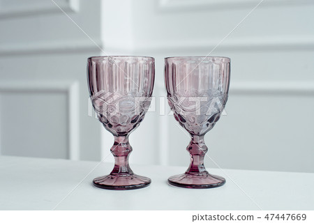Embossed colored drink glasses for wine on a white wooden table. Embossed colored drink glasses for wine on a white wooden table. 47447669