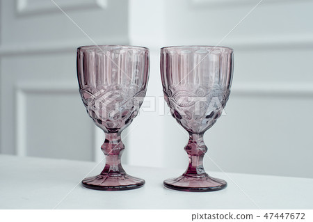 Embossed colored drink glasses for wine on a white wooden table. Embossed colored drink glasses for wine on a white wooden table. 47447672