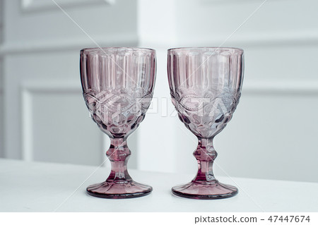 Embossed colored drink glasses for wine on a white wooden table. Embossed colored drink glasses for wine on a white wooden table. 47447674