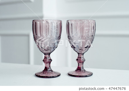 Embossed colored drink glasses for wine on a white wooden table. Embossed colored drink glasses for wine on a white wooden table. 47447676