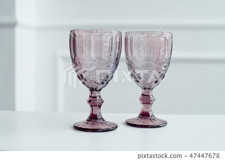 Embossed colored drink glasses for wine on a white wooden table. Embossed colored drink glasses for wine on a white wooden table. 47447678