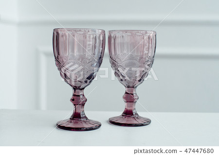 Embossed colored drink glasses for wine on a white wooden table. Embossed colored drink glasses for wine on a white wooden table. 47447680