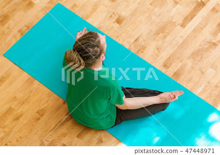 Man in a meditation pose inside a bright room 47448971