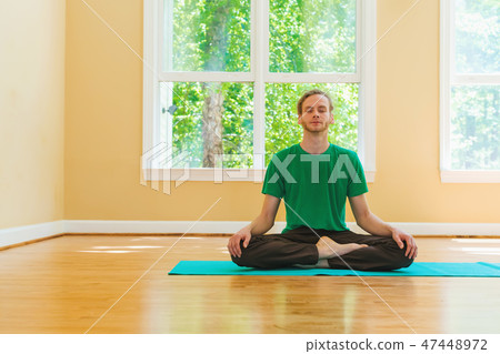 Man in a meditation pose inside a bright room Man in a meditation pose inside a bright room 47448972