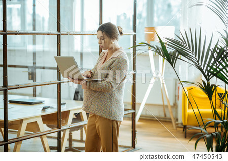 Pregnant successful businesswoman with hair bun holding laptop Pregnant successful businesswoman with hair bun holding laptop 47450543