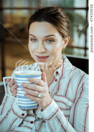 Close up of beautiful dark-haired woman holding big cup of tea Close up of beautiful dark-haired woman holding big cup of tea 47450856