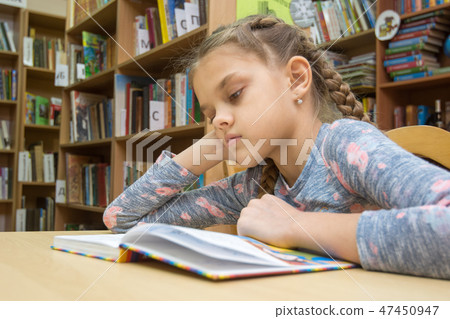 A girl of ten years old is reading a book in the reading room A girl of ten years old is reading a book in the reading room 47450947