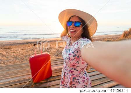 People, travelling and vacation concept - happy young woman with suitcase takes selfie portrait on People, travelling and vacation concept - happy young woman with suitcase takes selfie portrait on 47456844